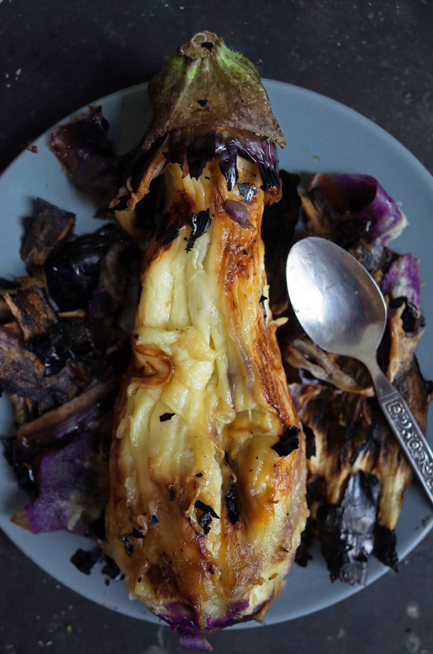 Flame Roasted Aubergine on a plate with the blackened skin peeling off