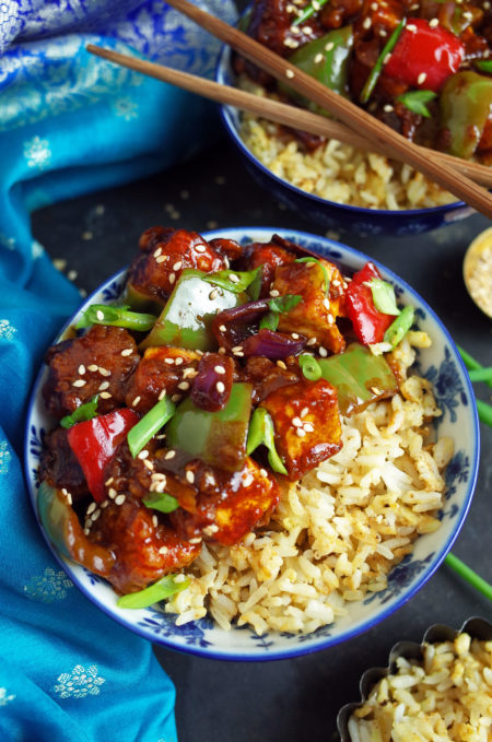 Crispy Vegan Indo-Chinese Chilli Tofu garnished with spring onions on a bed of Fried Rice in blue bowls