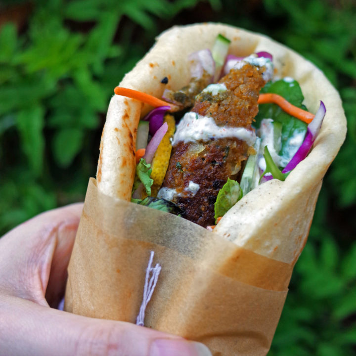 Vegan Seekh Kebab with salad in a homemade naan bread wrap. Wrapped in parchment paper for picnic transportation