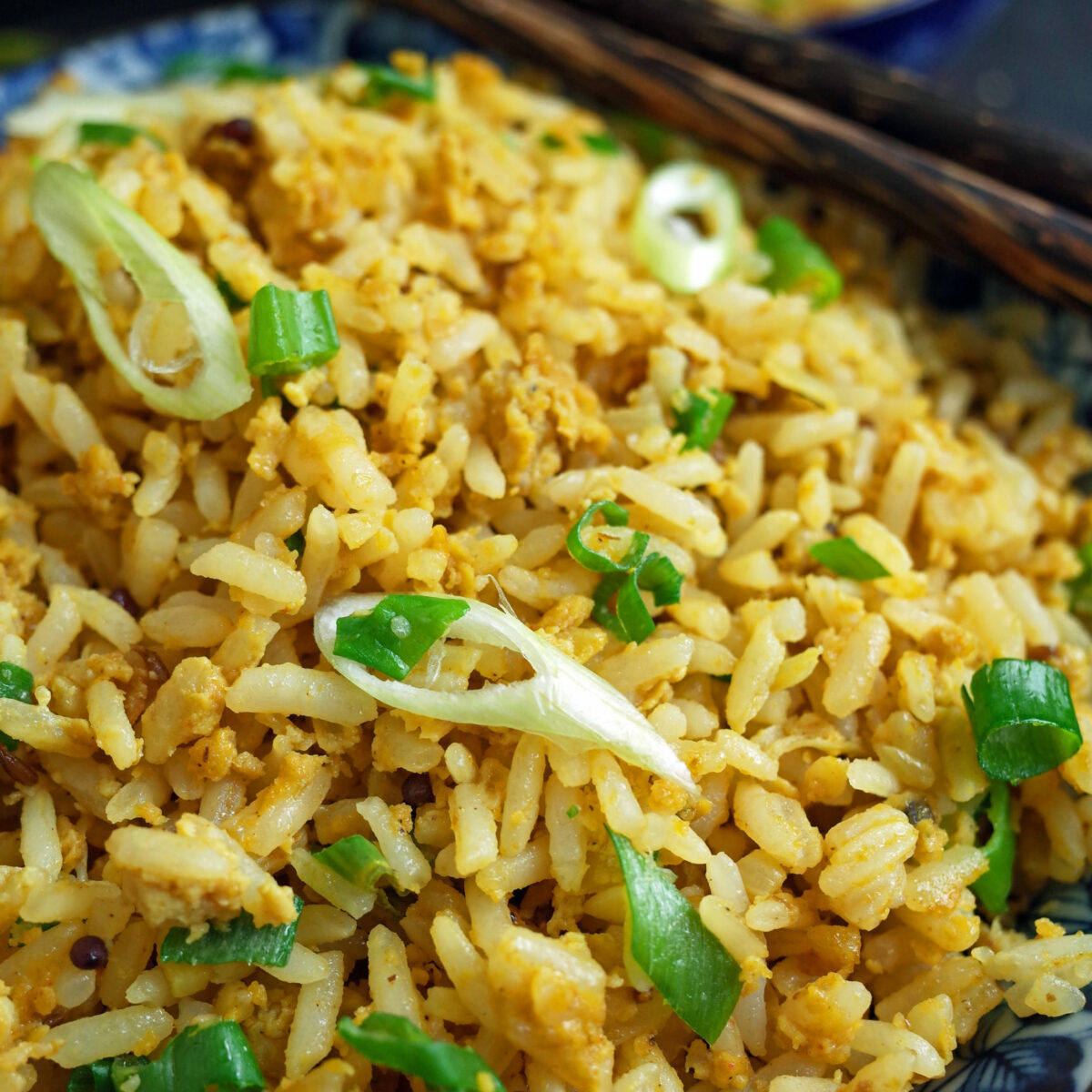 Indian Egg Fried Rice topped with Spring Onion in a blue bowl