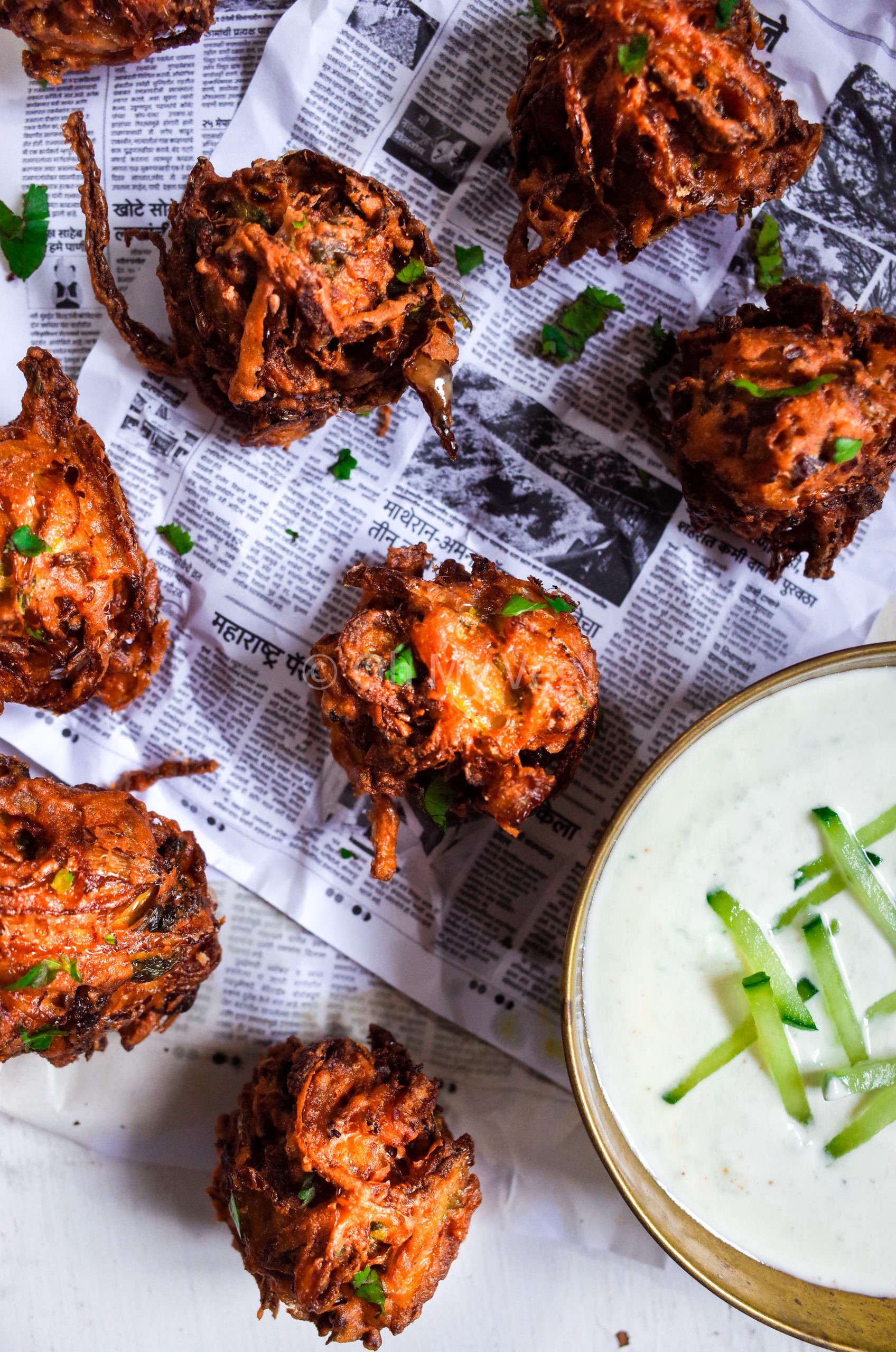 Crispy onion bhaji sprinkled with coriander on newspaper sheets 