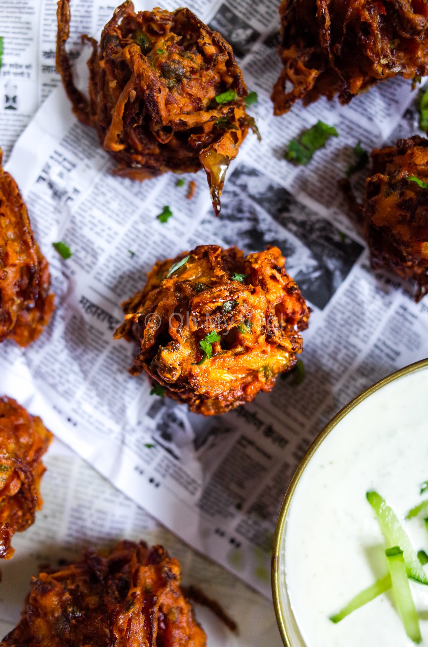 A crispy onion bhaji sitting on a Maharashtrian newspaper sheet 