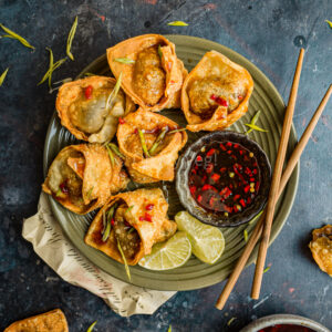 Fried vegan mushroom wontons with lime and sweet chili sauce on a plate