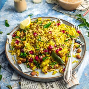 Maharashtrian kanda batata poha on a plate with a teapot in the background