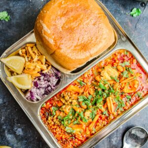 Misal pav on a plate with farsan and onion.