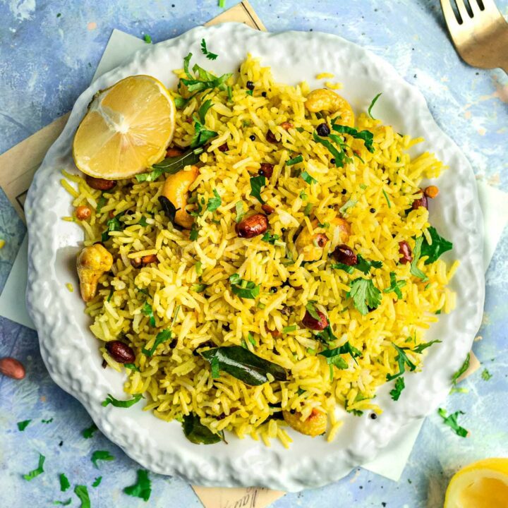 Chitranna or South Indian lemon rice, on a plate with fresh herbs.