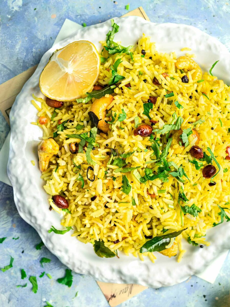 Chitranna or South Indian lemon rice on a white plate and blue background, close-up. 