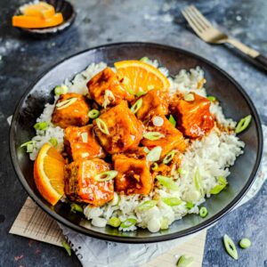 Vegan orange tofu on a plate with rice.