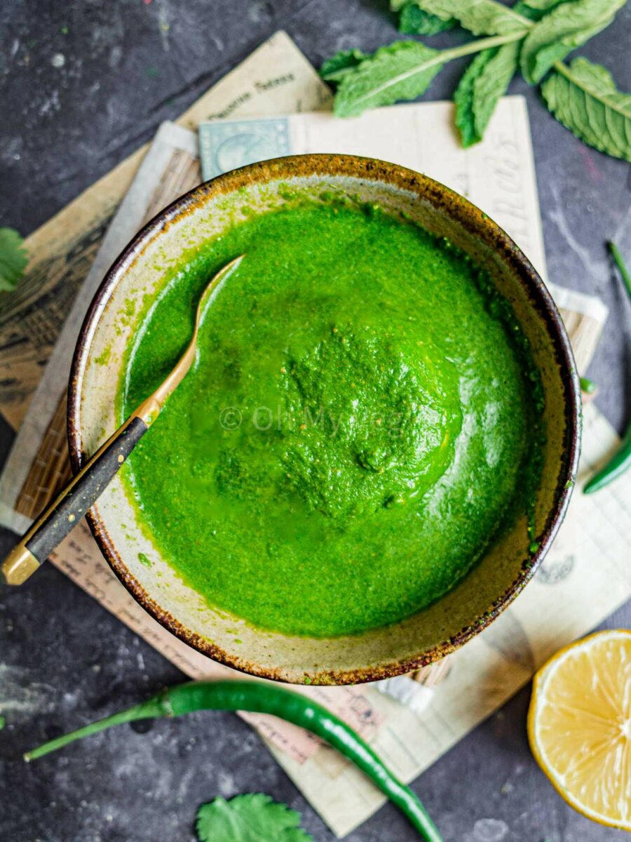 Indian green chutney in a brown bowl with a spoon.