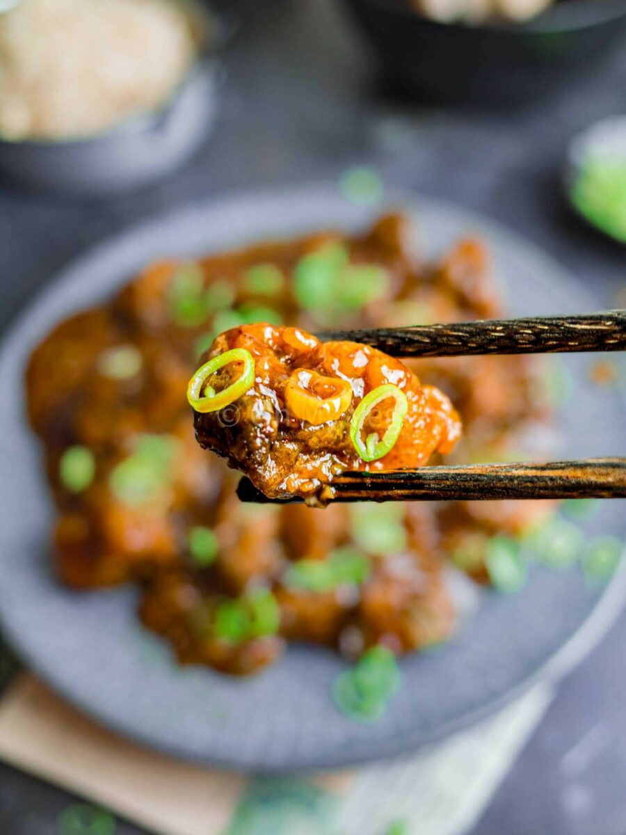 Chopsticks holding a piece of battered mushroom.