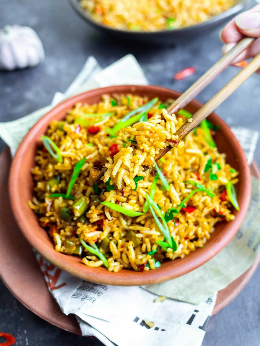 Person using chopsticks to serve spicy rice. 