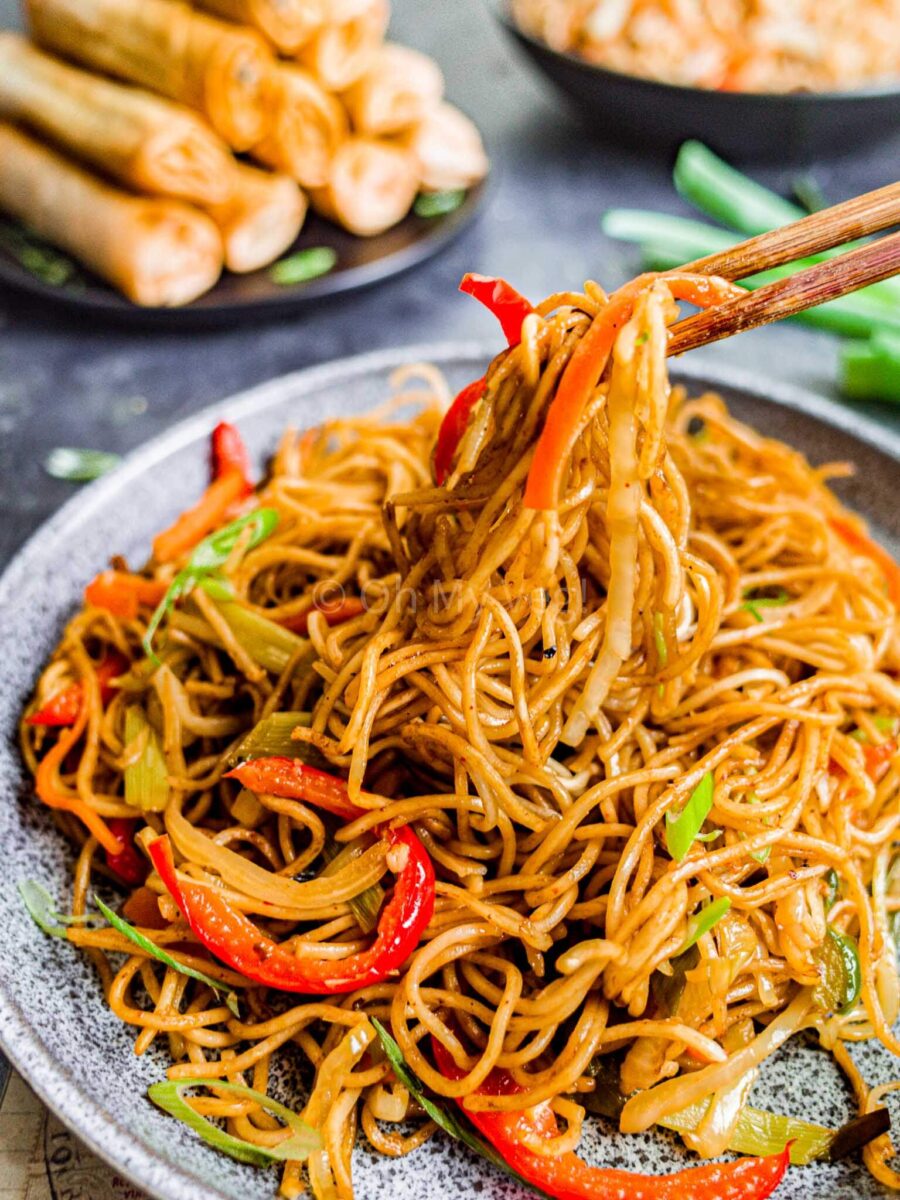 Chopsticks holding vegetable hakka noodles.