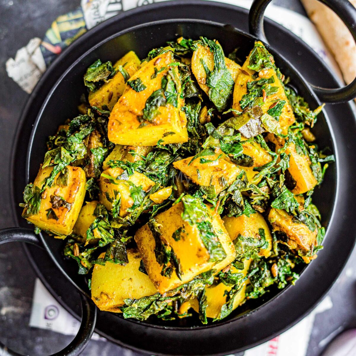 Aloo methi in a black kadai.