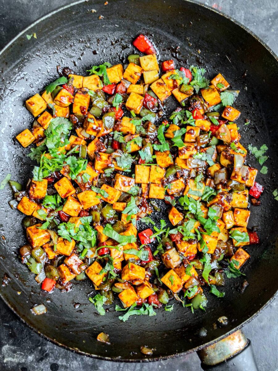 Chilli paneer in a black frying pan.