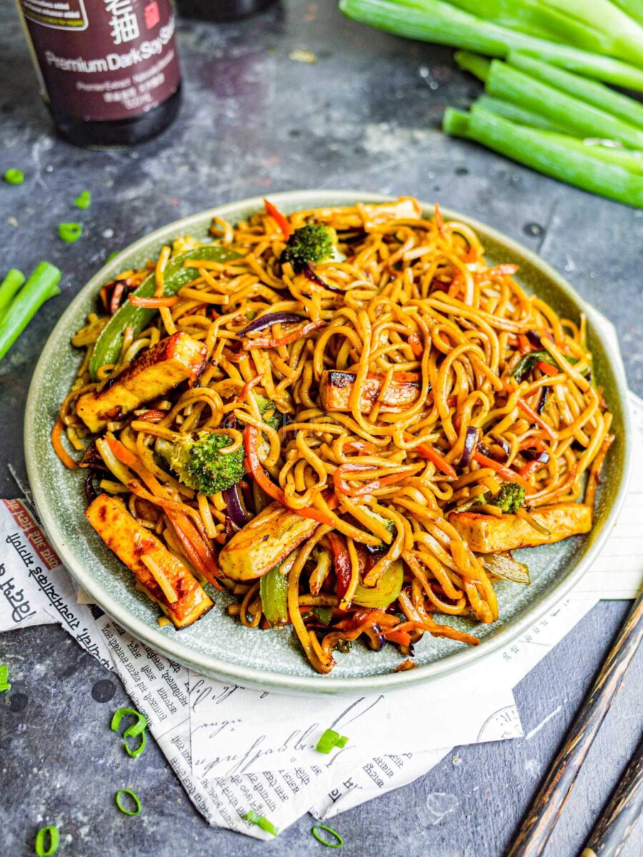 A green plate full of paneer hakka noodles.