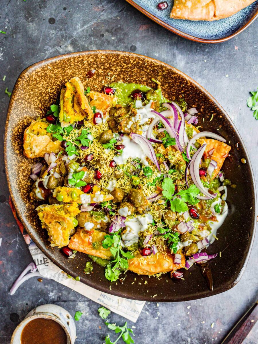 Samosa chaat in a plate, topped with onions.