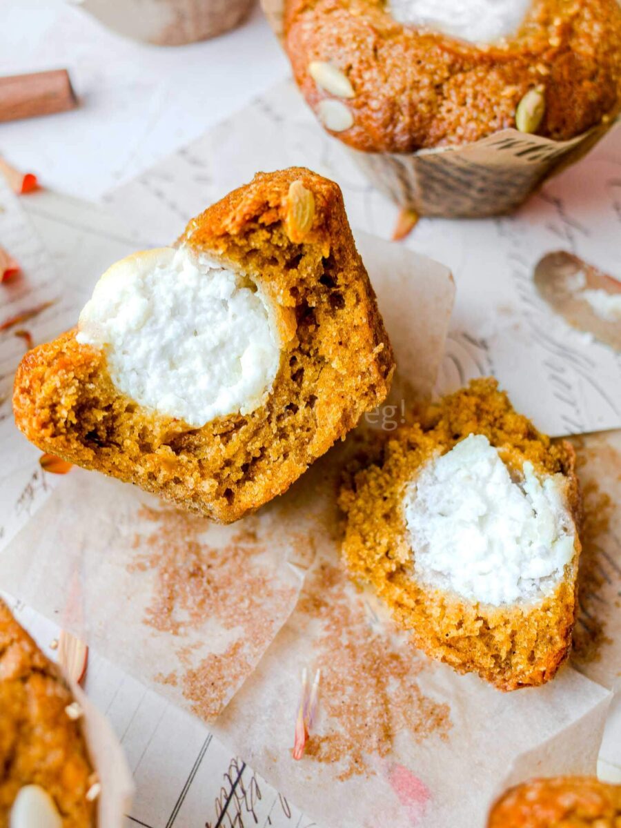 Pumpkin muffins cut in half showing the cream cheese filling. 