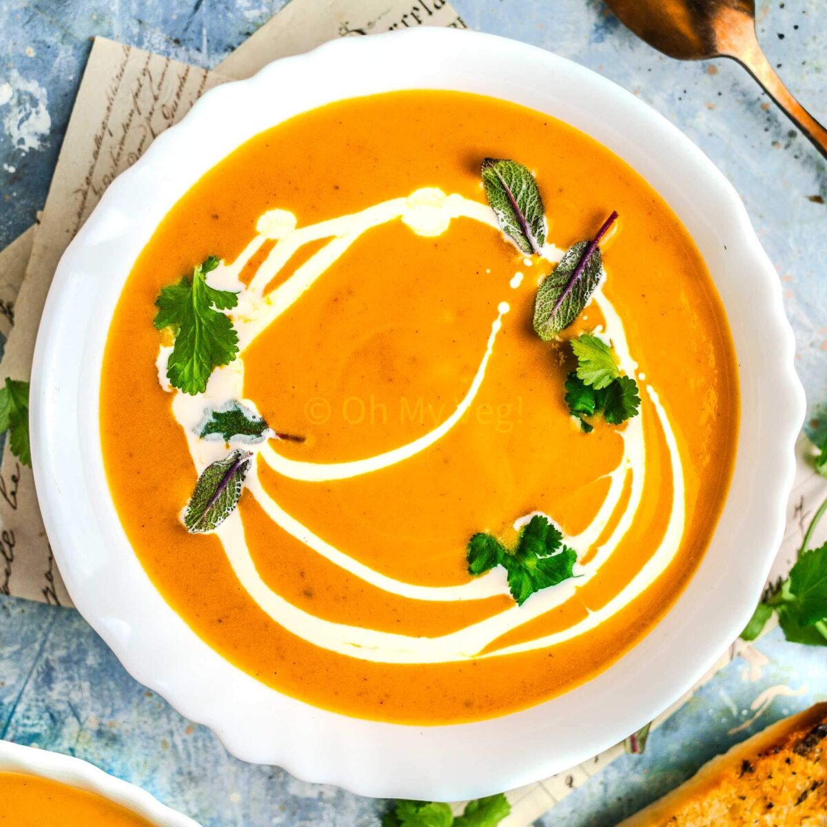 Pumpkin and sweet potato soup in a white bowl, on a blue background. 