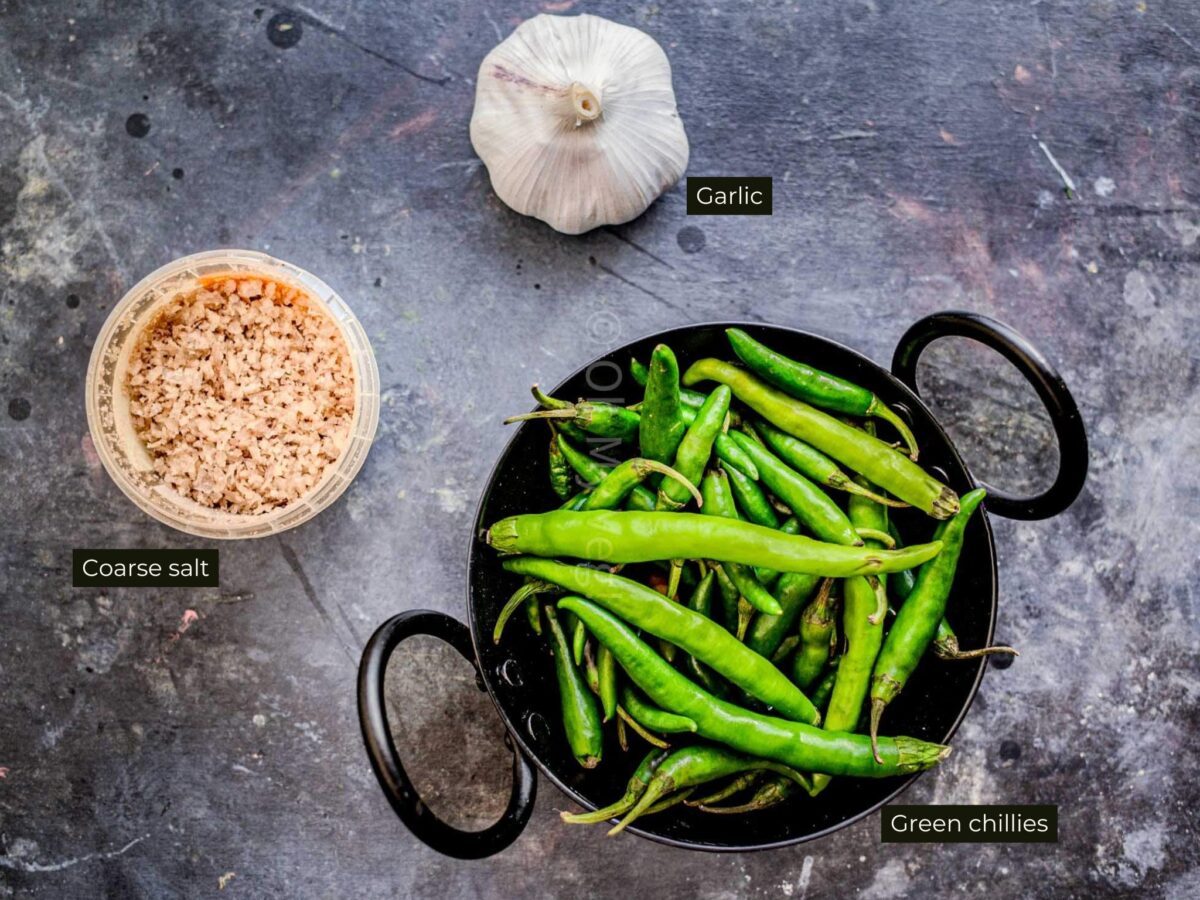 Green chilli thecha ingredients on a black background. 