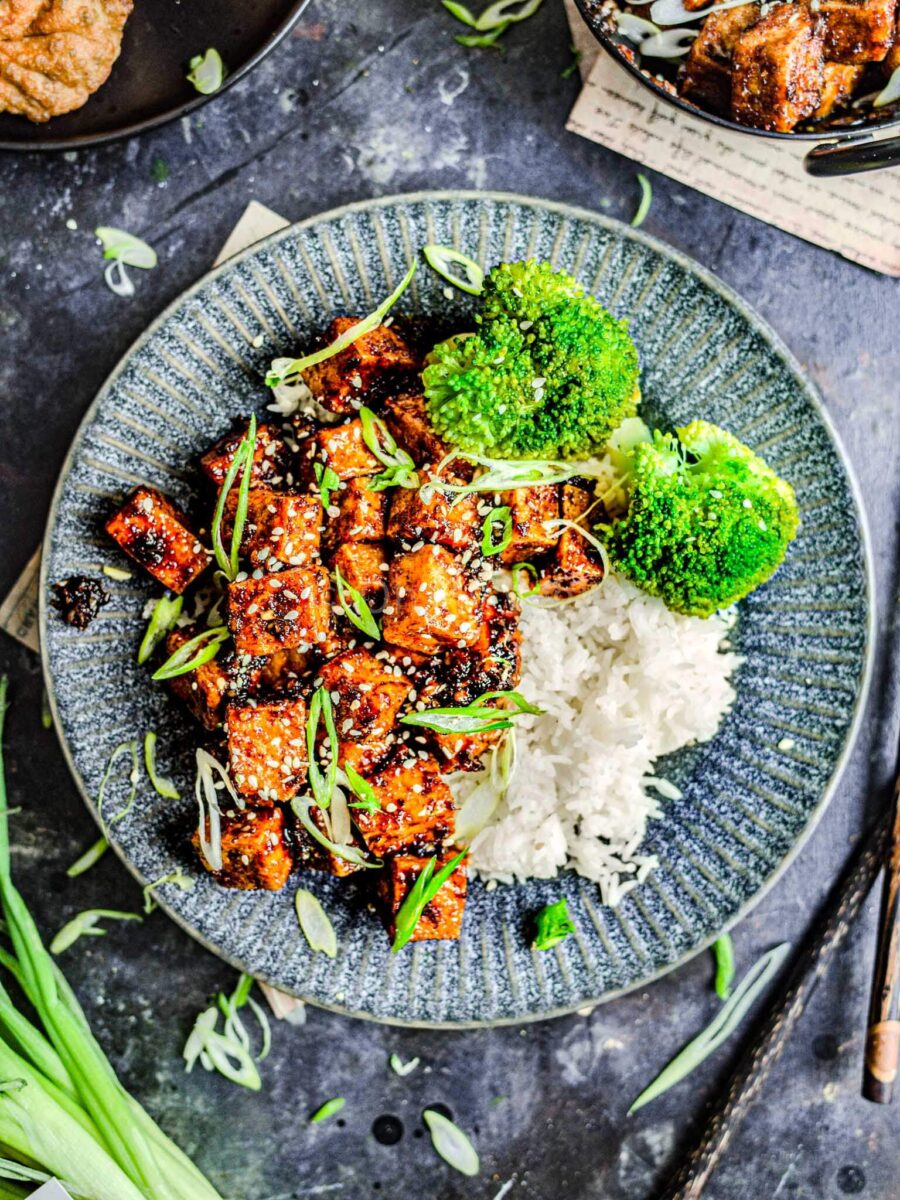 Honey garlic tofu with rice and broccoli on a grey plate. 