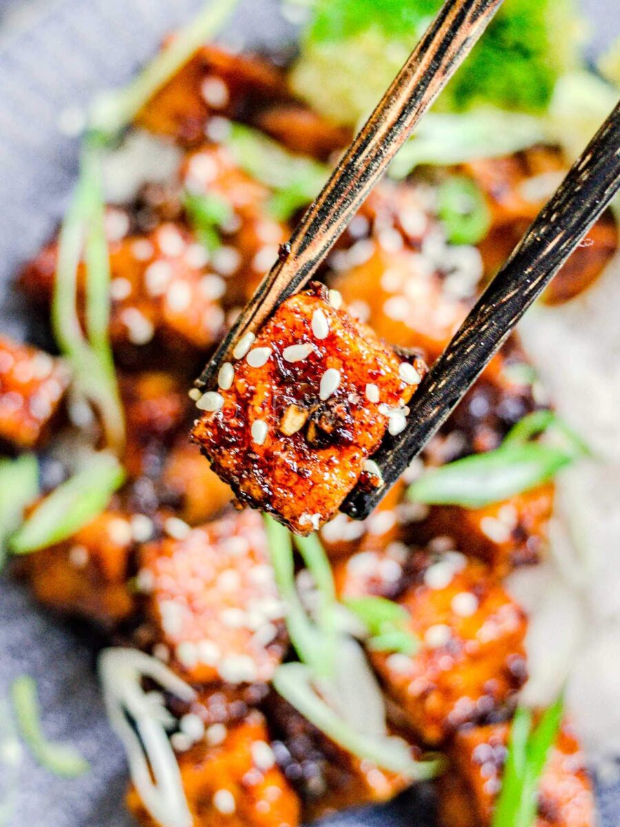 Chopsticks holding crispy honey tofu.