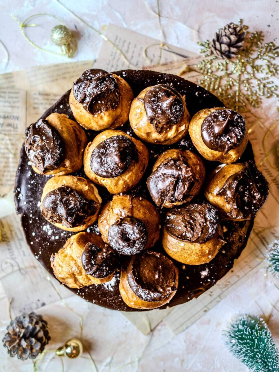 Profiterole cheesecake from above, on a festive beige background.