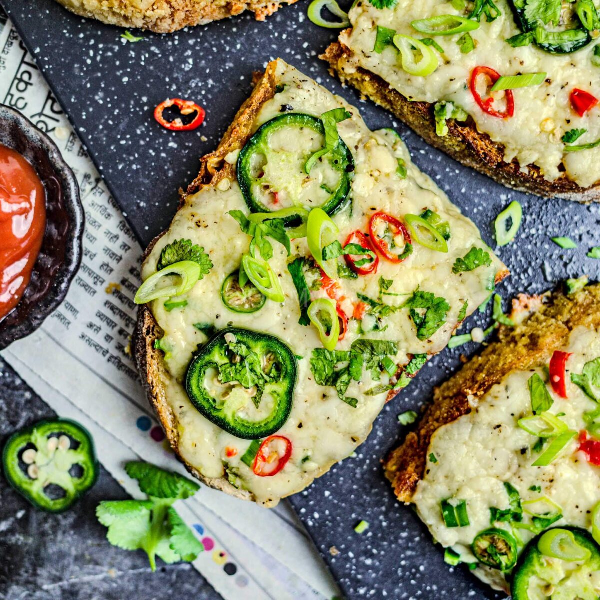 Chilli cheese toast with ketchup, on a board.