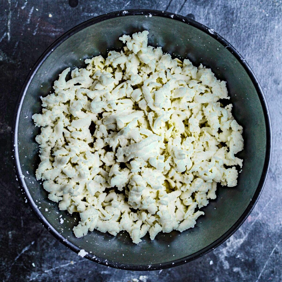 Mozzarella grated into a black bowl.