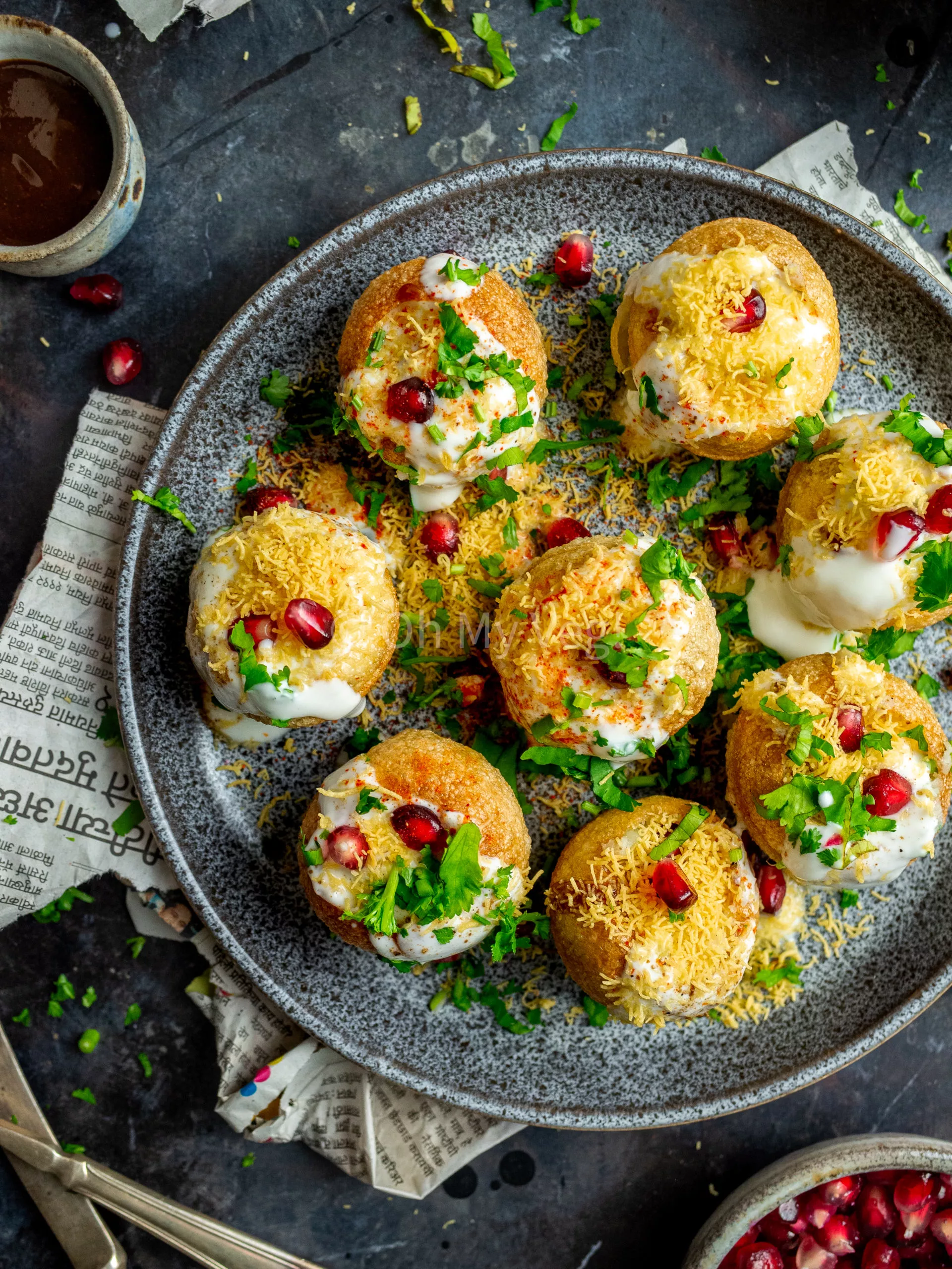 Indian dahi puri on a plate, topped with sev and pomegranate