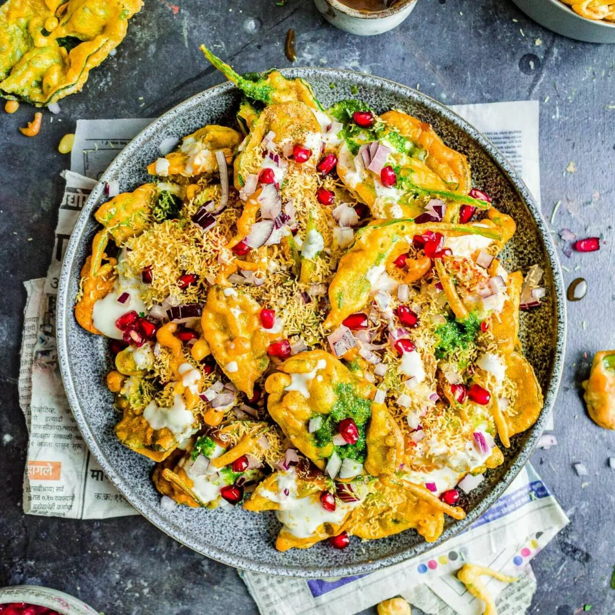 Palak chaat on a grey plate, with chutney bowls on the side.